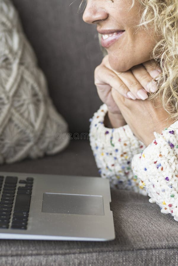 Nah an Frau lächeln und glücklichen Laptop auf dem Sofa benutzen. fröhliche Frau vor dem Computer. Internetsurfer zu Hause lizenzfreie stockfotografie