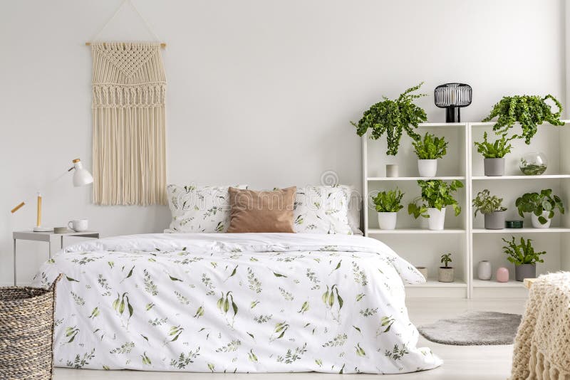 Nah an hellem Schlafzimmerinnenraum der Natur mit vielen Grünpflanzen neben einem großen Bett Gesponnene Tapisserie über dem Bett lizenzfreie stockfotografie Nah an hellem Schlafzimmerinnenraum der Natur mit vielen Grünpflanzen neben einem großen Bett Gesponnene Tapisserie über dem Bett lizenzfreie stockfotografie