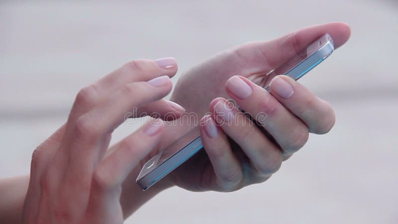 Nahaufnahme der Hände der Frau mit der netten simsenden Maniküre, Mitteilung am intelligenten Telefon