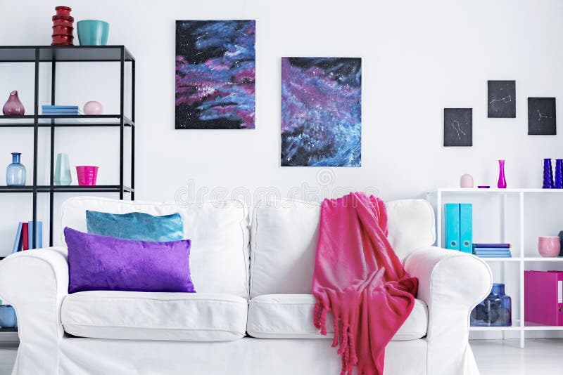 Closeup of white comfortable couch with pink blanket and purple and blue pillows in modern living room interior, real photo concept. Closeup of white comfortable couch with pink blanket and purple and blue pillows in modern living room interior, real photo concept