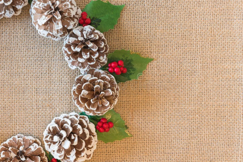 Nahaufnahme des flachen gelegten Weihnachtskranzes von pinecones, von roten Beeren und von Stechpalmenblättern auf rustikalem Gew lizenzfreies stockbild Nahaufnahme des flachen gelegten Weihnachtskranzes von pinecones, von roten Beeren und von Stechpalmenblättern auf rustikalem Gew lizenzfreies stockbild