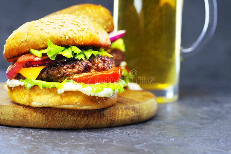 Nahaufnahme des köstlichen Rindfleischburgers auf einem hölzernen Brett mit einem Glas Bier stockfoto Nahaufnahme des köstlichen Rindfleischburgers auf einem hölzernen Brett mit einem Glas Bier stockfoto