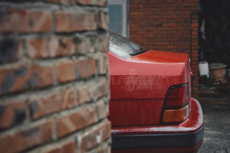 Nahaufnahme eines lebhaften roten Autos, das in einem klassischen Backsteinhaus parkiert ist stockbild