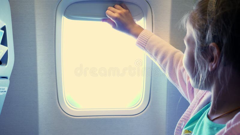 Nahaufnahme Kind, das Mädchen den Öffnungsschleier in der Kabine des Flugzeuges, von dort lüftet, glänzt ein helles Licht Herrlic