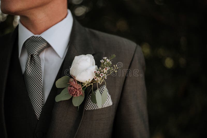 Nahaufnahme schoss von einem Mann, der ein Smoking mit einem Boutonniere in seiner Tasche trägt lizenzfreie stockbilder Nahaufnahme schoss von einem Mann, der ein Smoking mit einem Boutonniere in seiner Tasche trägt lizenzfreie stockbilder