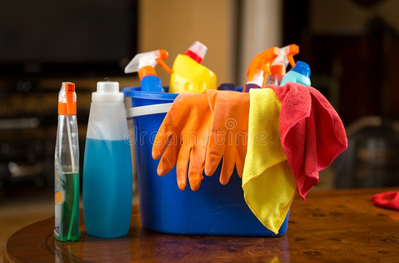 Closeup photo of cleaning chemicals, gloves and rags lying in plastic bucket. Closeup photo of cleaning chemicals, gloves and rags lying in plastic bucket