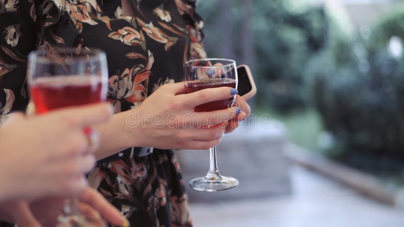 Nahaufnahme von den zwei Händen der Frauen mit Gläsern Rotwein
