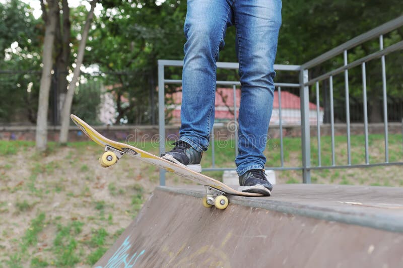 Nahaufnahme von Fußturnschuhen und von Jeans eines Skateboardfahrers vor dem Rennen stockbild Nahaufnahme von Fußturnschuhen und von Jeans eines Skateboardfahrers vor dem Rennen stockbild