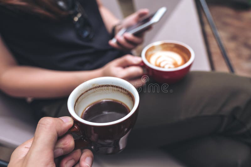 Nahaufnahmebild einer Mann ` s Hand, die schwarze Kaffeetasse mit einer Frau verwendet Smartphone beim Trinken des Kaffees hält stockfoto Nahaufnahmebild einer Mann ` s Hand, die schwarze Kaffeetasse mit einer Frau verwendet Smartphone beim Trinken des Kaffees hält stockfoto