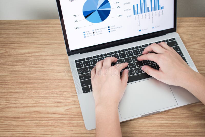 Nahaufnahmebilder von H?nden auf den Laptops, die Finanzdiagramme auf dem Schirm auf einem braunen Holztisch zeigen stockfotografie Nahaufnahmebilder von H?nden auf den Laptops, die Finanzdiagramme auf dem Schirm auf einem braunen Holztisch zeigen stockfotografie
