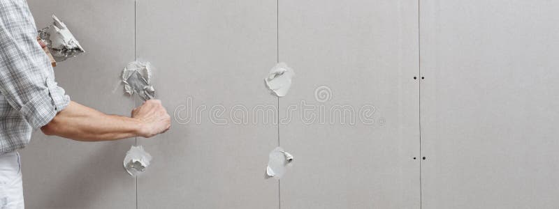 Nahaufnahmehandmanntrockenmauerarbeitskraft oder -Gipser, die auf Stuck Gipskartonwand mithilfe einer Kelle und einer Spachtel, di lizenzfreies stockfoto