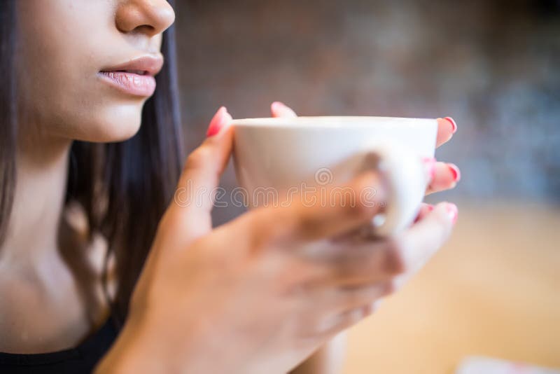 Nahaufnahmeporträt der jungen Frau einen Tasse Kaffee in den Händen halten stockfotografie Nahaufnahmeporträt der jungen Frau einen Tasse Kaffee in den Händen halten stockfotografie