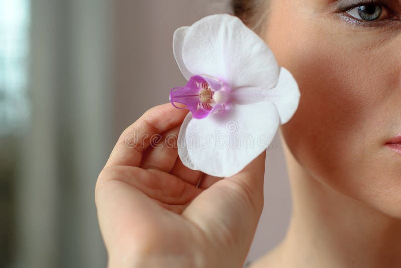 Nahaufnahmeporträt eines Mädchens mit Orchideenblume in ihrer Hand lizenzfreies stockfoto Nahaufnahmeporträt eines Mädchens mit Orchideenblume in ihrer Hand lizenzfreies stockfoto