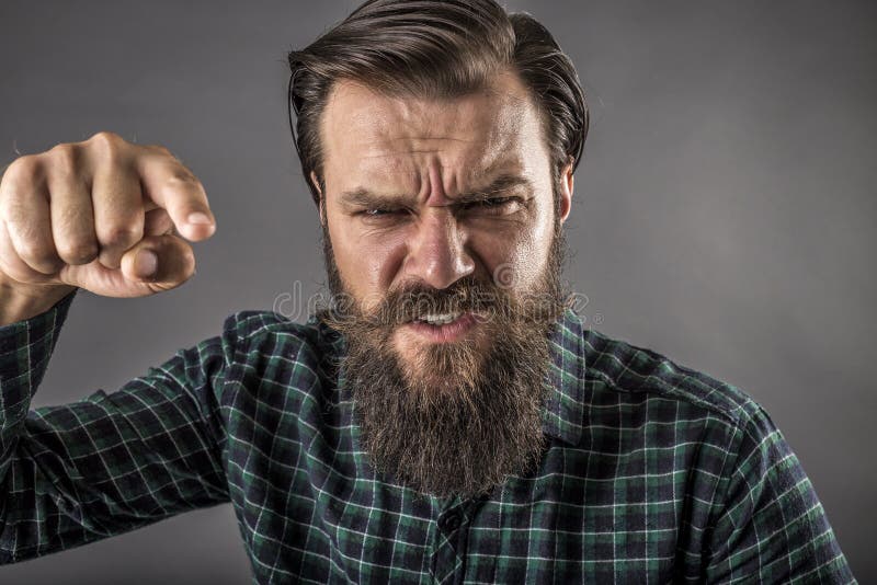 Nahaufnahmeporträt eines verärgerten bärtigen Mannes, der mit seiner FI droht lizenzfreies stockbild Nahaufnahmeporträt eines verärgerten bärtigen Mannes, der mit seiner FI droht lizenzfreies stockbild