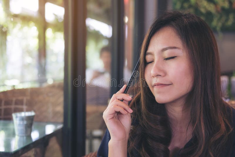 Nahaufnahmeporträtbild einer schönen Asiatin, die ihre Augen schließt und im modernen Café beim Denken an Geschäft sitzt stockfoto Nahaufnahmeporträtbild einer schönen Asiatin, die ihre Augen schließt und im modernen Café beim Denken an Geschäft sitzt stockfoto