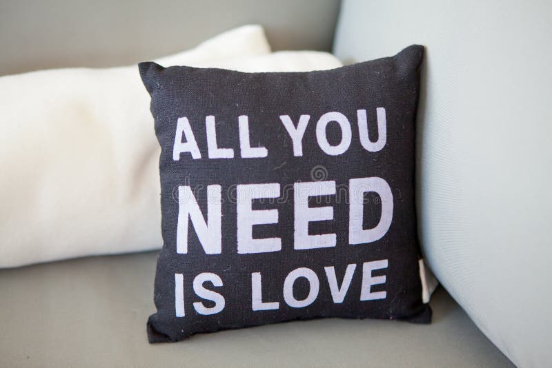 Nahaufnahmeschwarzalles Kissen mit einer Aufschrift, das Sie benötigen, ist Liebe auf einer hellen Couch mit Kissen, selektiver F lizenzfreie stockfotos Nahaufnahmeschwarzalles Kissen mit einer Aufschrift, das Sie benötigen, ist Liebe auf einer hellen Couch mit Kissen, selektiver F lizenzfreie stockfotos