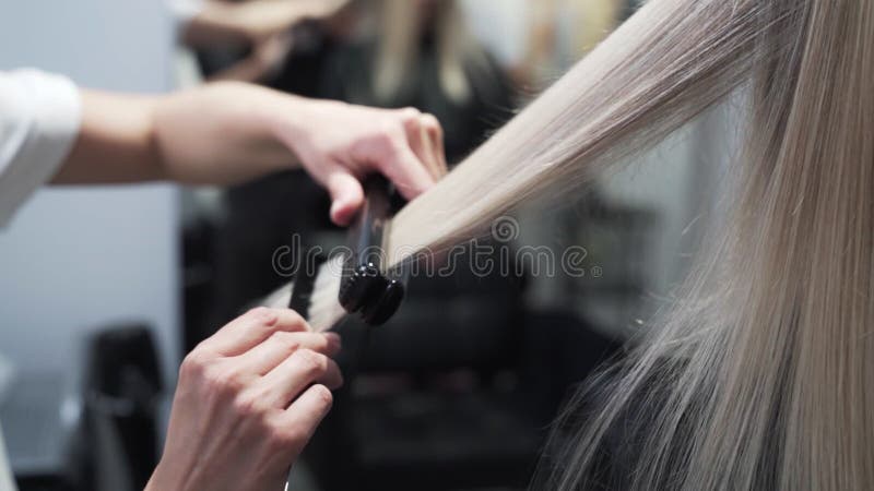 Nahe gelegen, Friseur Styling langen blonden Frau Haar mit Haar-Richtmaschine