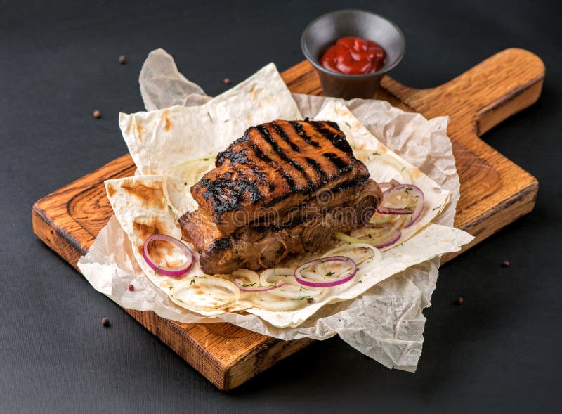 Nahe an würzig gegrillten Rippen auf dunklem Hintergrund mit Kopierraum. Fleisch auf Holzbrett lizenzfreies stockfoto