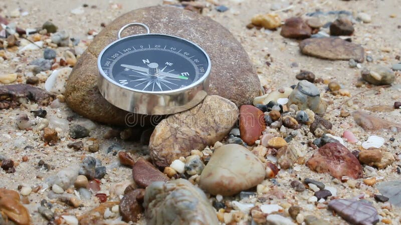 Naher hoher Schuss der Neigung des Kompassses auf dem Felsen und Sand setzen mit Naturseeumgebendem Ton auf den Strand