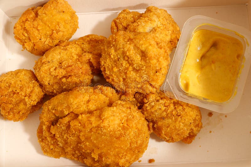 Nahes hohes Foto eines Haufens der Hühnernuggets und des Plastikbehälters mit Currybadsoße stockfotografie Nahes hohes Foto eines Haufens der Hühnernuggets und des Plastikbehälters mit Currybadsoße stockfotografie