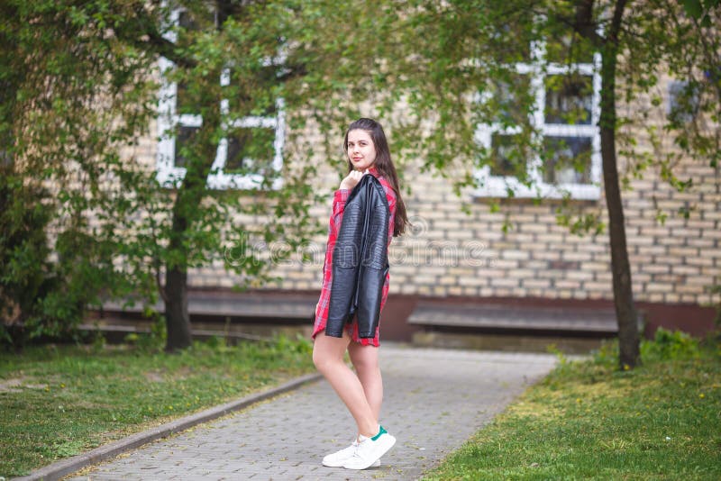 Nahes hohes Portr?t des sch?nen stilvollen M?dchens der gro?en Plusgr??e Kindermit Lederjacke und rotem kariertem Hemd nahe Backs lizenzfreies stockfoto Nahes hohes Portr?t des sch?nen stilvollen M?dchens der gro?en Plusgr??e Kindermit Lederjacke und rotem kariertem Hemd nahe Backs lizenzfreies stockfoto