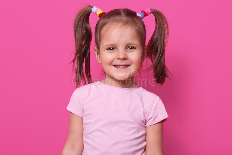 Nahes hohes Portr?t des netten s??en kleinen M?dchens mit den lustigen Z?pfen, herzlichst l?chelnd und betrachten direkt Kamera, lizenzfreies stockfoto Nahes hohes Portr?t des netten s??en kleinen M?dchens mit den lustigen Z?pfen, herzlichst l?chelnd und betrachten direkt Kamera, lizenzfreies stockfoto