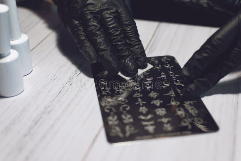 Nail Art Stamping process. Manicure master makes Stamping with nail gel polish, Stamping Plates and Transparent Stamper Scraper stock image Nail Art Stamping process. Manicure master makes Stamping with nail gel polish, Stamping Plates and Transparent Stamper Scraper stock image