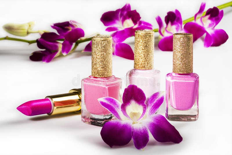 Esmalte de unas, lápiz labial a flores en blanco.