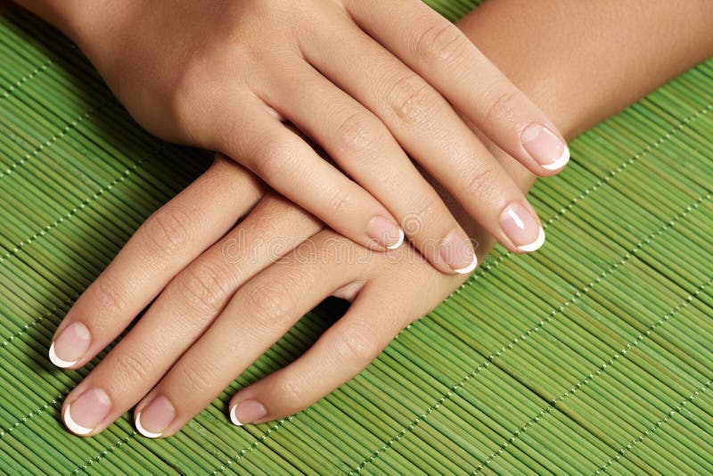 Beautiful womans nails with perfect french manicure on natural wood background. Care for female hands. Natural look with light nail polish, beauty care. Beautiful womans nails with perfect french manicure on natural wood background. Care for female hands. Natural look with light nail polish, beauty care.