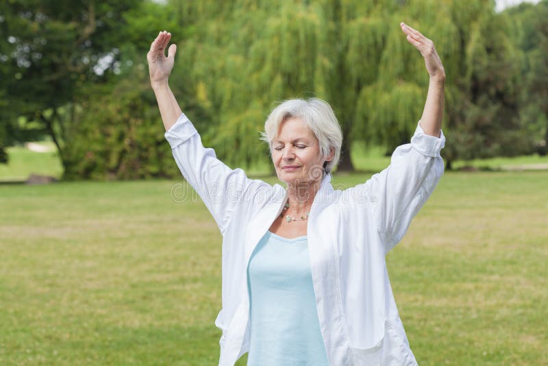 Best ager woman practising yoga and tai chi outdoors. Best ager woman practising yoga and tai chi outdoors