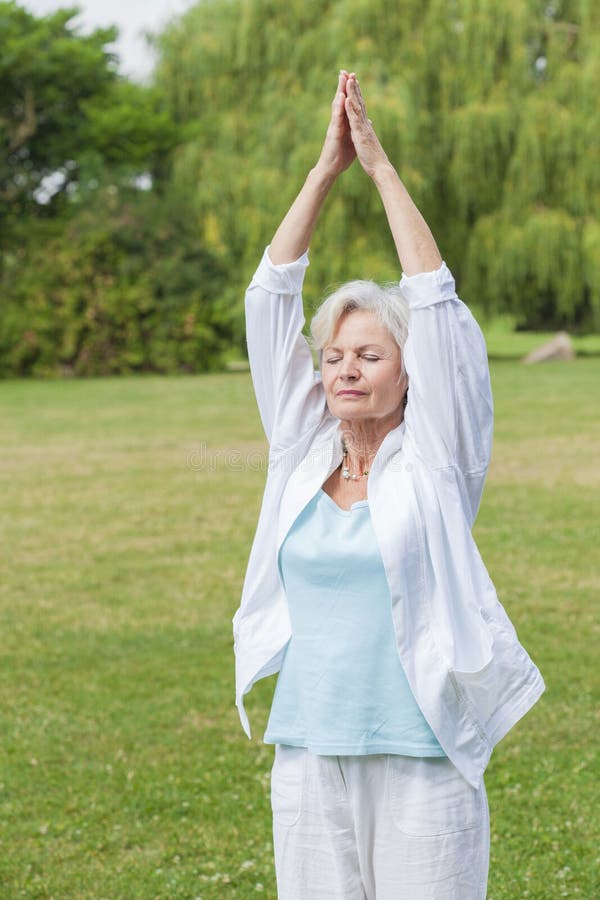 Best ager woman practising yoga and tai chi outdoors. Best ager woman practising yoga and tai chi outdoors