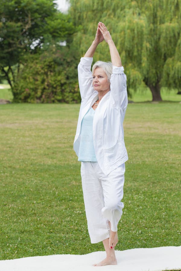 Best ager woman practising yoga and tai chi outdoors. Best ager woman practising yoga and tai chi outdoors