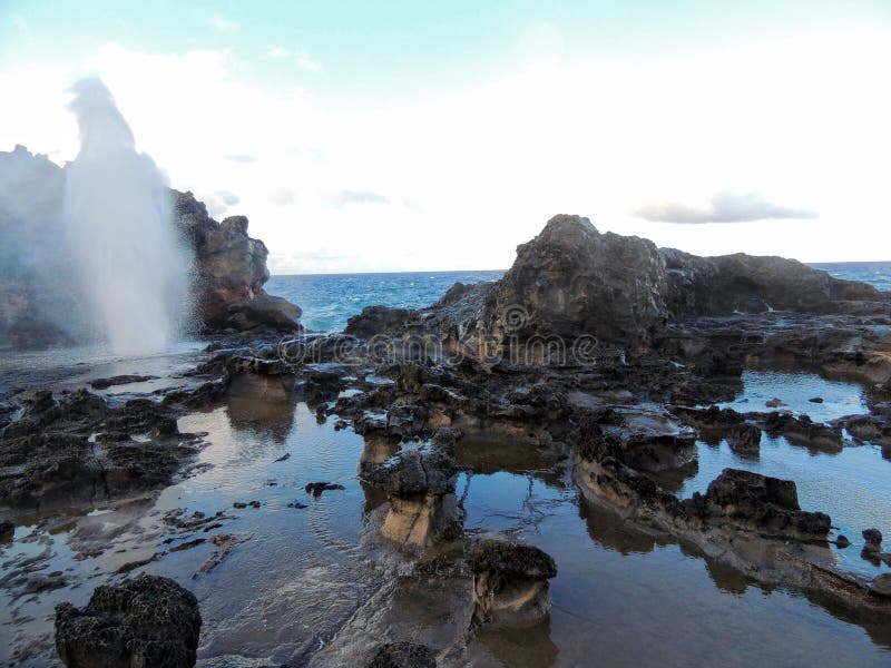 Nakalele Blowhole with water spraying out that was created from Pacific Ocean waves hitting the tall rocky cliff coastline that wa