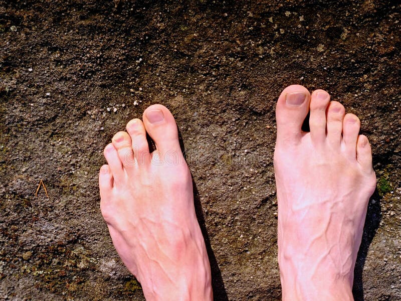 Naked male legs on peak make step. Sandstone rock above valley with tired hikers legs. royalty free stock image Naked male legs on peak make step. Sandstone rock above valley with tired hikers legs. royalty free stock image