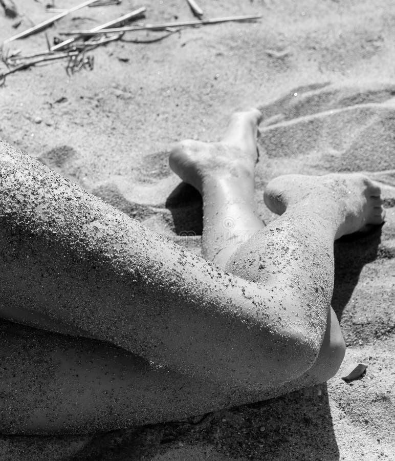 Naked woman covered by sand resting on a sandy beach