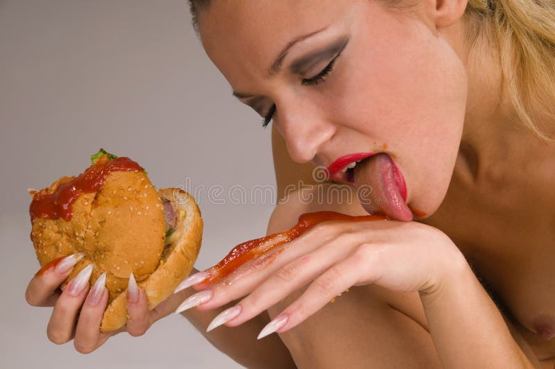Naked woman eating a hamburger. 
