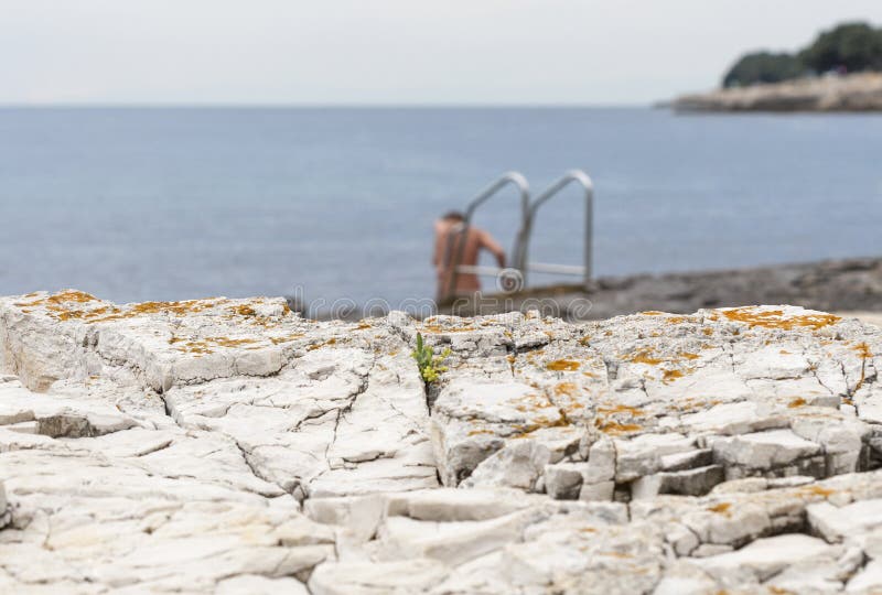 Naken kvinnabadning i den steniga stranden för hav med stegen royaltyfri fotografi Naken kvinnabadning i den steniga stranden för hav med stegen royaltyfri fotografi