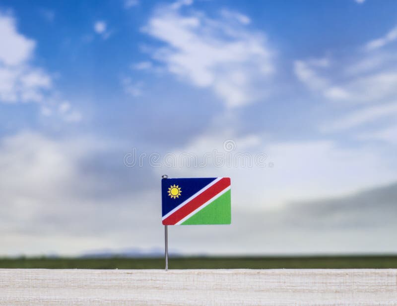 Namibia flag with vast meadow and blue sky behind it. stock photography