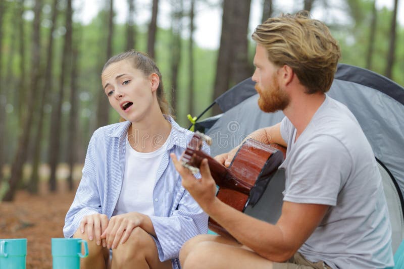 Namorada cantando enquanto parceiro tocando violão fora da tenda fotos de stock