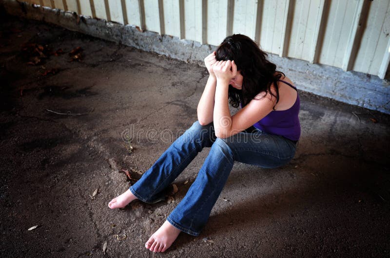 Photo illustration of sexual assault - traumatized woman sit on the floor of empty warehouse. Photo illustration of sexual assault - traumatized woman sit on the floor of empty warehouse.