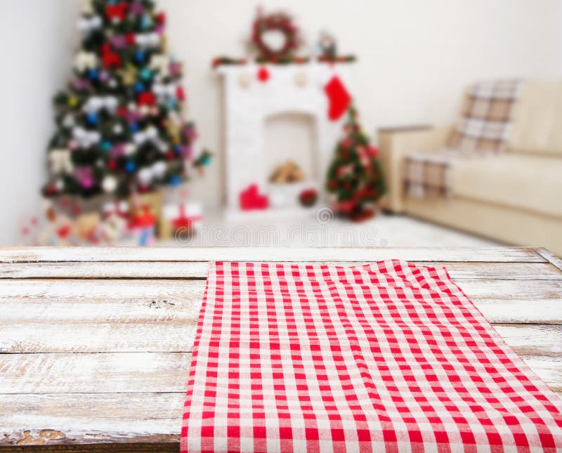Checkered red tablecloth on wooden table on blurred holiday interior, new year and christmas concept, tablecloths. Checkered red tablecloth on wooden table on blurred holiday interior, new year and christmas concept, tablecloths.
