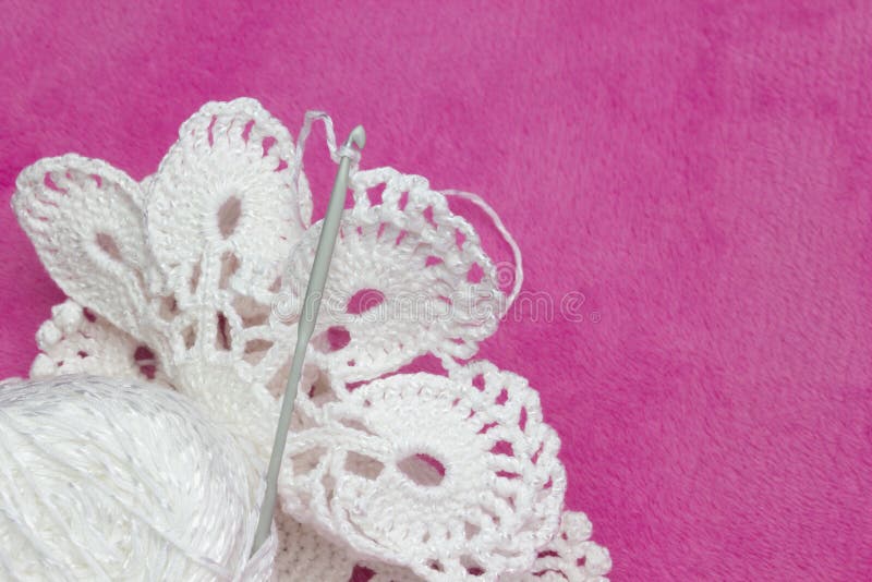 Napperon blanc de vintage Fils de coton pour le crochet de tricotage et de crochet Photo du processus de crochet sur le fond rose images stock Napperon blanc de vintage Fils de coton pour le crochet de tricotage et de crochet Photo du processus de crochet sur le fond rose images stock