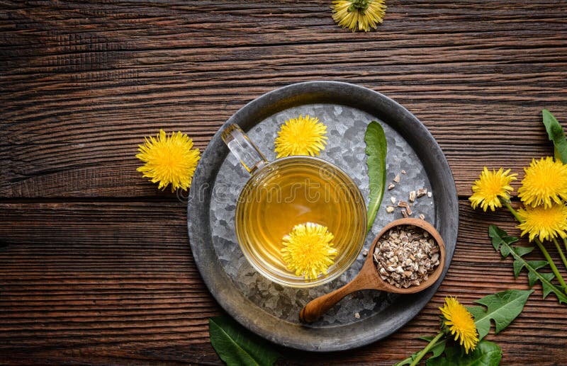 Napój ziołowy na herbatę detox dandelion w szklanym kubku ozdobionym świeżymi kwiatami z kopią
