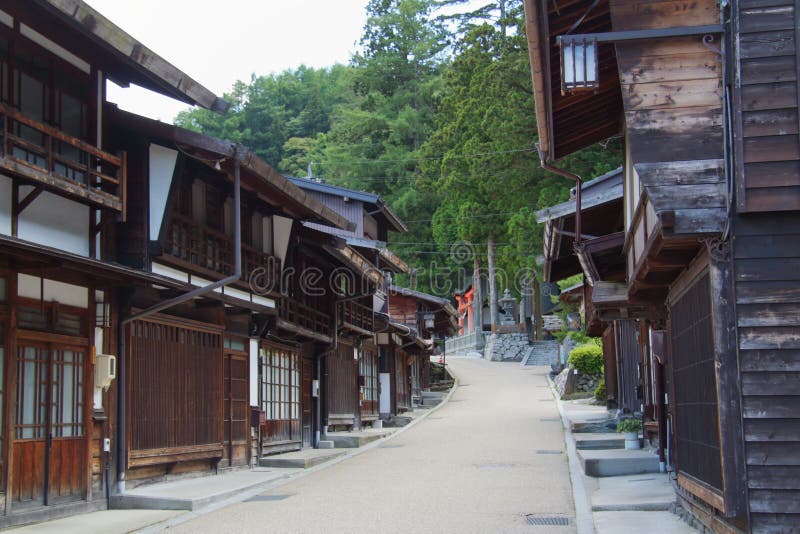 The street of Narai-juku with a red torii gate and a Shito temple in the distance. Traditional Edo period houses and shops. The street of Narai-juku with a red torii gate and a Shito temple in the distance. Traditional Edo period houses and shops.