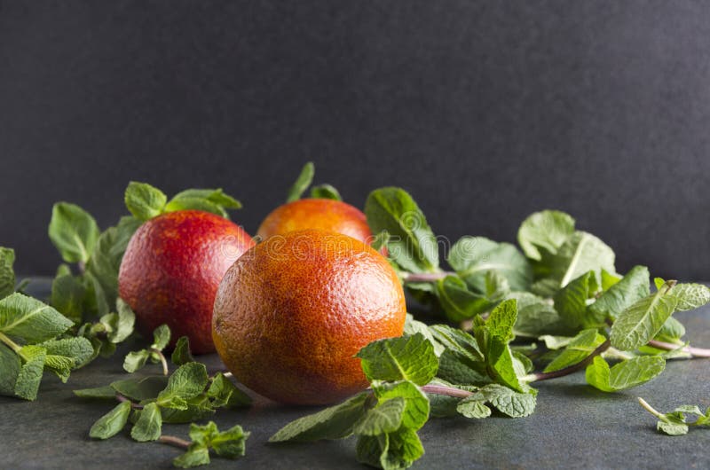 Naranjas de sangre frescas con la menta en la tabla rústica contra fondo negro Hierbas del nad de las frutas jugosas, frescas imagen de archivo libre de regalías Naranjas de sangre frescas con la menta en la tabla rústica contra fondo negro Hierbas del nad de las frutas jugosas, frescas imagen de archivo libre de regalías