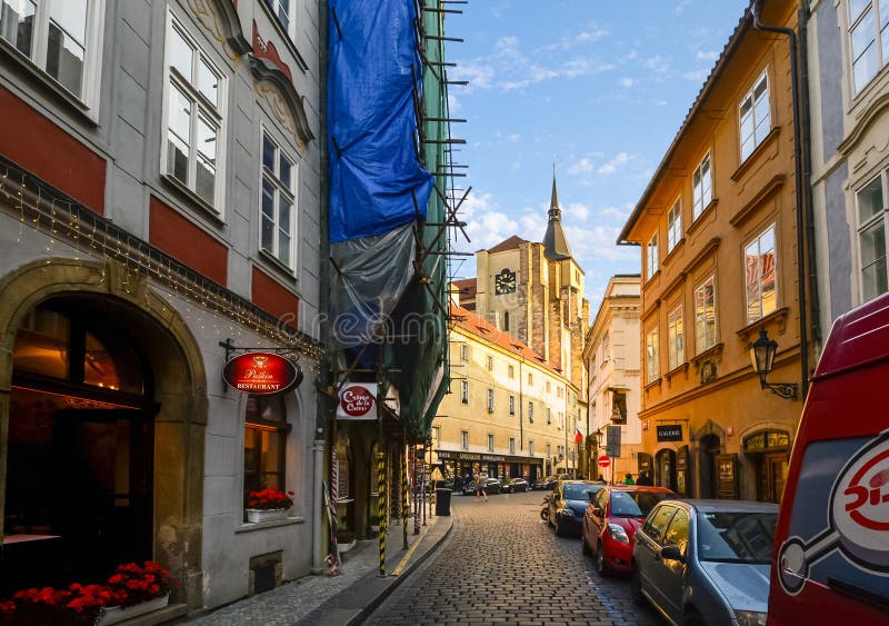 A narrow street lined with cars and a truck in Prague, Czech Republic as sunlight highlights a church spire in the Male Strana dis stock images A narrow street lined with cars and a truck in Prague, Czech Republic as sunlight highlights a church spire in the Male Strana dis stock images