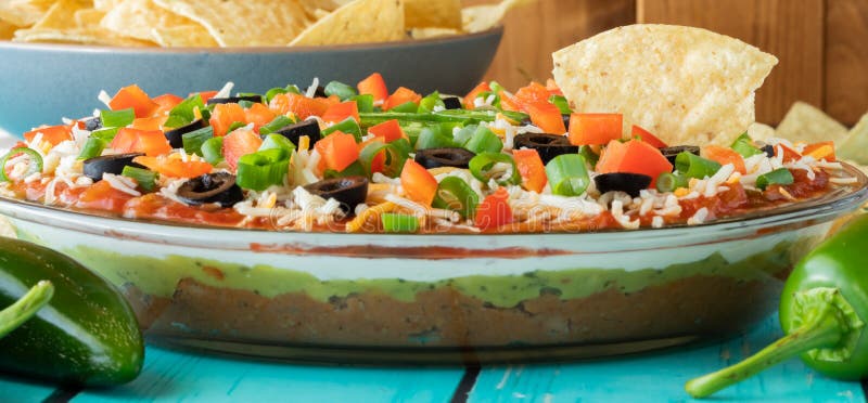 A narrow view of a homemade 7 layer dip with one tortilla chip sticking out.