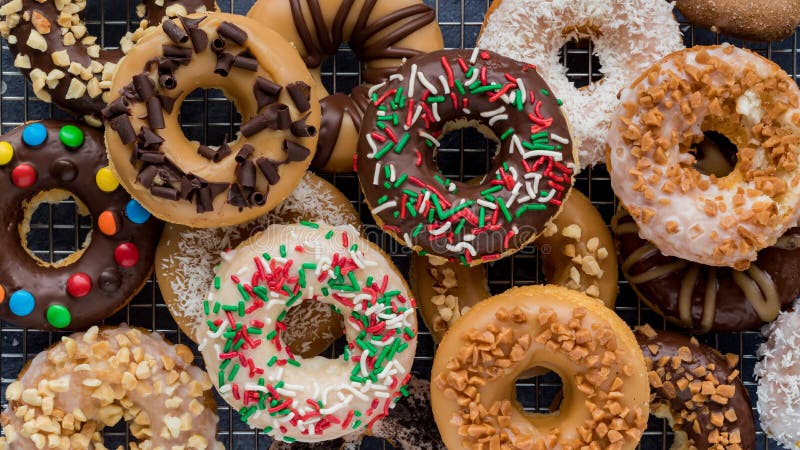 Narrow view of a pile of homemade donuts with various glazes and toppings.