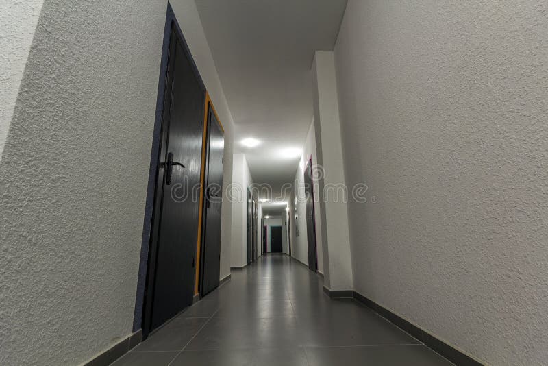 Narrow white corridor with many doors in an apartment building stock photo Narrow white corridor with many doors in an apartment building stock photo