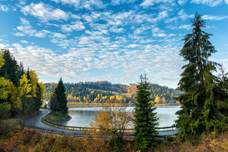 Úzká klikatá cesta podél jezera, podzimní krajina